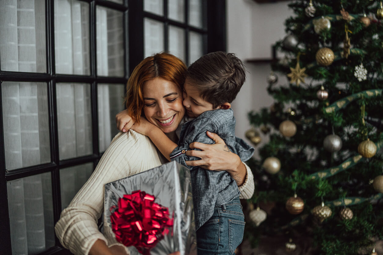 Mother and child with present by Christmas tree after creating a new custody agreement.